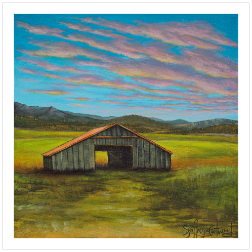 Archival print on matte paper of a contemporary rural landscape with a rustic barn sitting in a green field with mountains in the distance and a blue sky with pink and yellow sunset clouds.