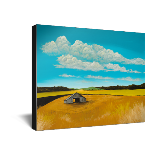Archival print on canvas of a contemporary rural landscape painting of a rustic barn sitting in a yellow field with green hills in the distance under a blue sky filled with white fluffy clouds. 