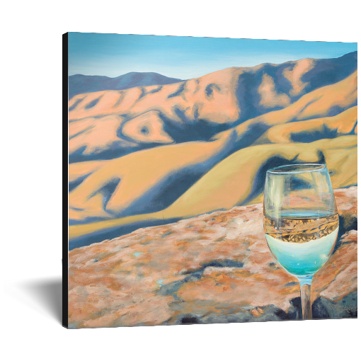 Archival print on canvas of a glass of white wine refracting sunlit foothills under a bright blue sky. 